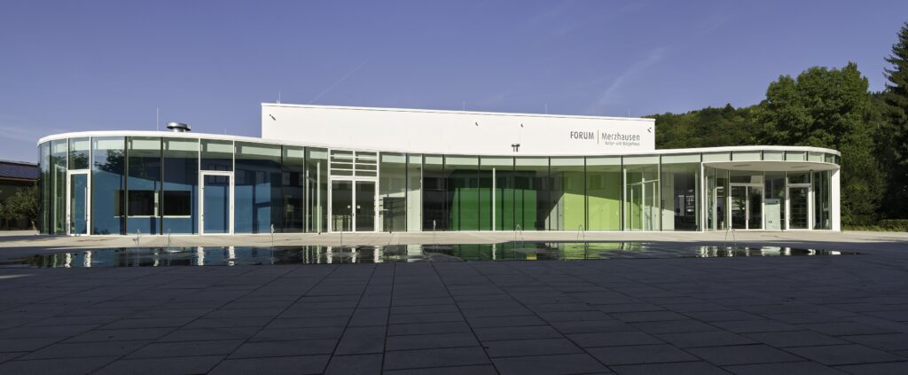 Kultur- und Bürgerhaus Forum Merzhausen mit gläserner Fassade vor bewaldetem Hang im südlichen Breisgau