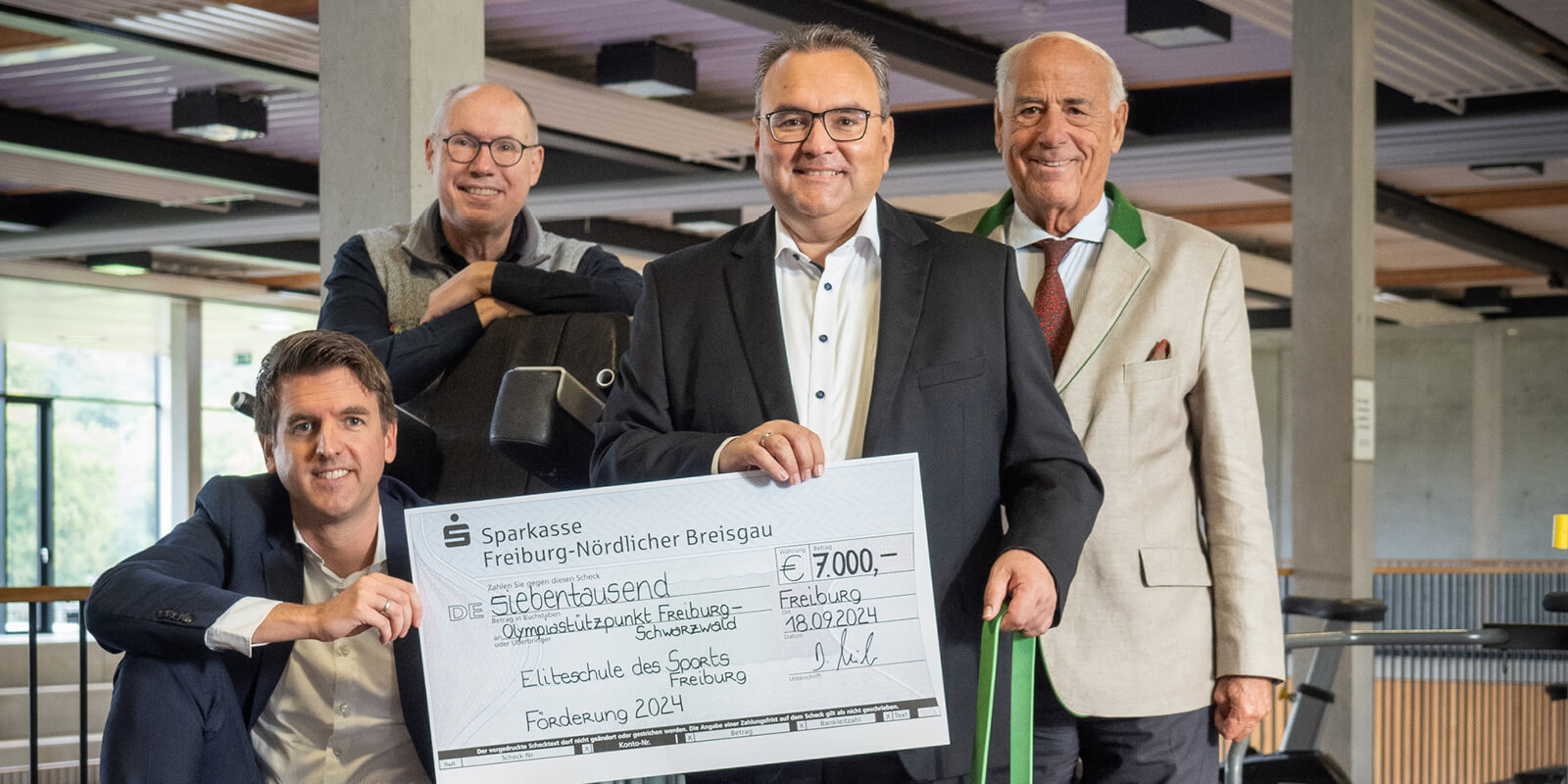 Scheckübergabe über 7.000 Euro an den Olympiastützpunkt Freiburg: Alexander Jacobs und Daniel Zeiler von der Sparkasse mit Jürgen Willrett und Gundolf Fleischer in sportlicher Umgebung der Eliteschule des Sports
