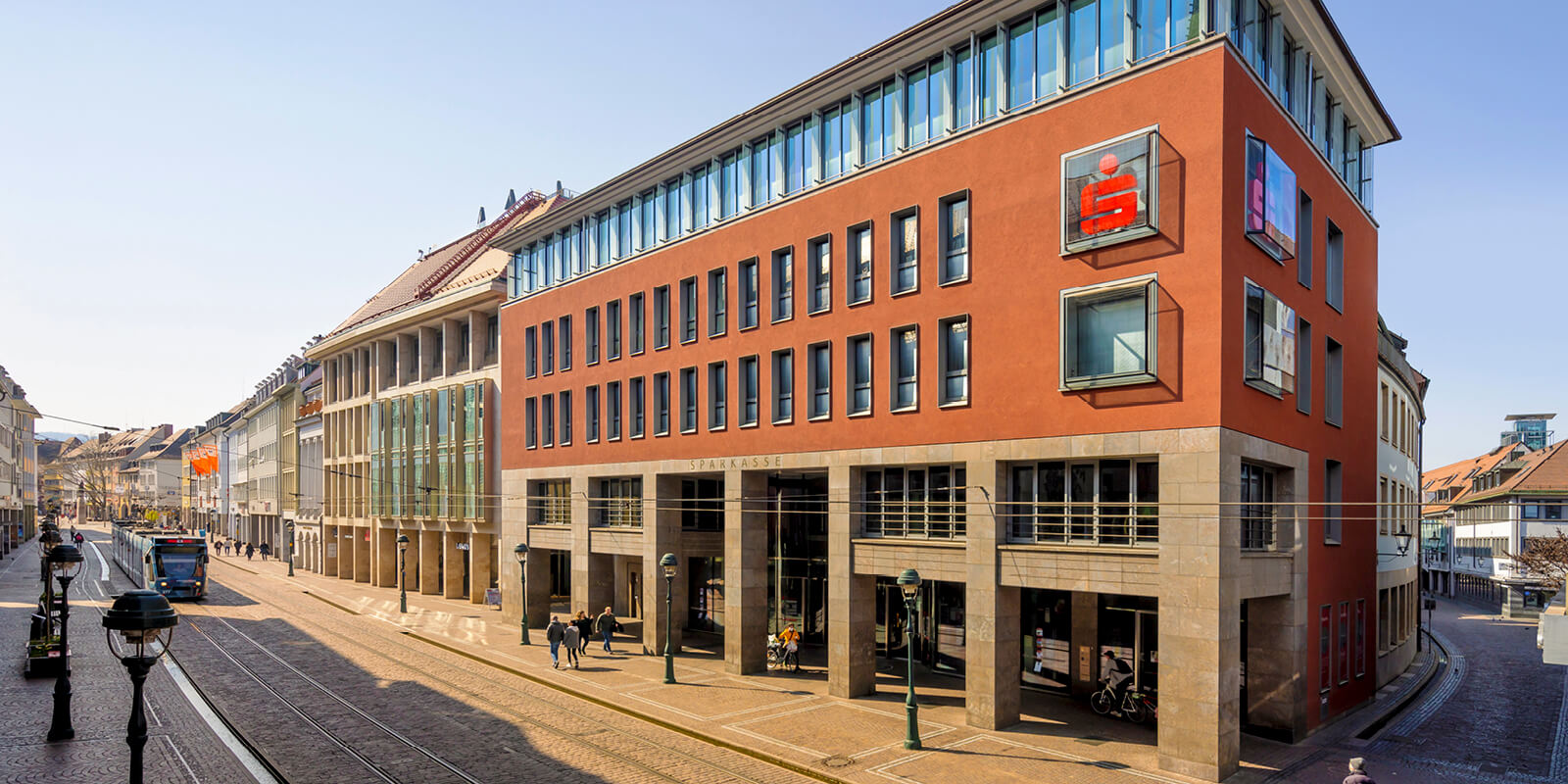 Außenansicht des FinanzZentrums Freiburg der Sparkasse Freiburg-Nördlicher Breisgau in der Kaiser-Joseph-Straße, mit Straßenbahn und Fußgängerzone