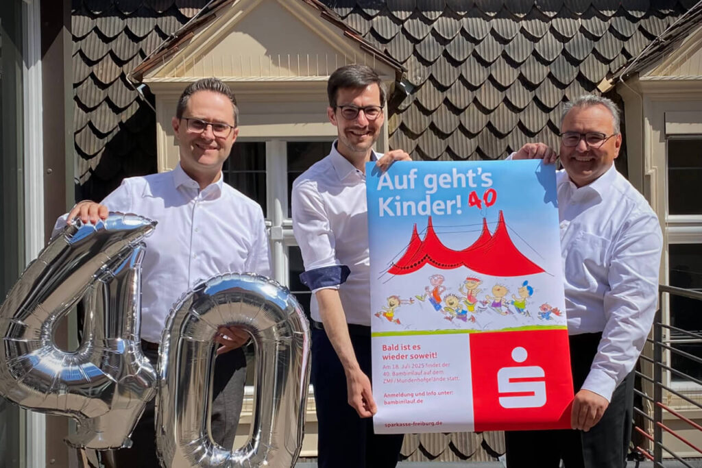 Marc Winsheimer, OB Martin Horn und Sparkassenvorstand Daniel Zeiler halten Plakat und Luftballons zum 40. Bambinilauf in Freiburg.