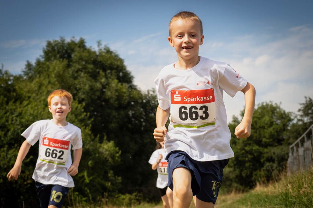 Teilnehmende des Bambinilaufs 2025 auf dem Mundenhof in Freiburg mit Startnummern und Bambinilauf-T-Shirts beim Lauf.