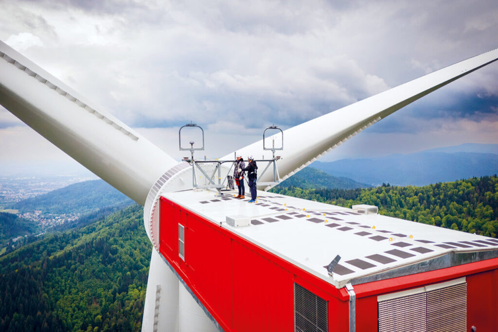 Zwei Personen stehen auf dem Maschinenhaus eines Windrads auf dem Taubenkopf bei Freiburg im Schwarzwald.