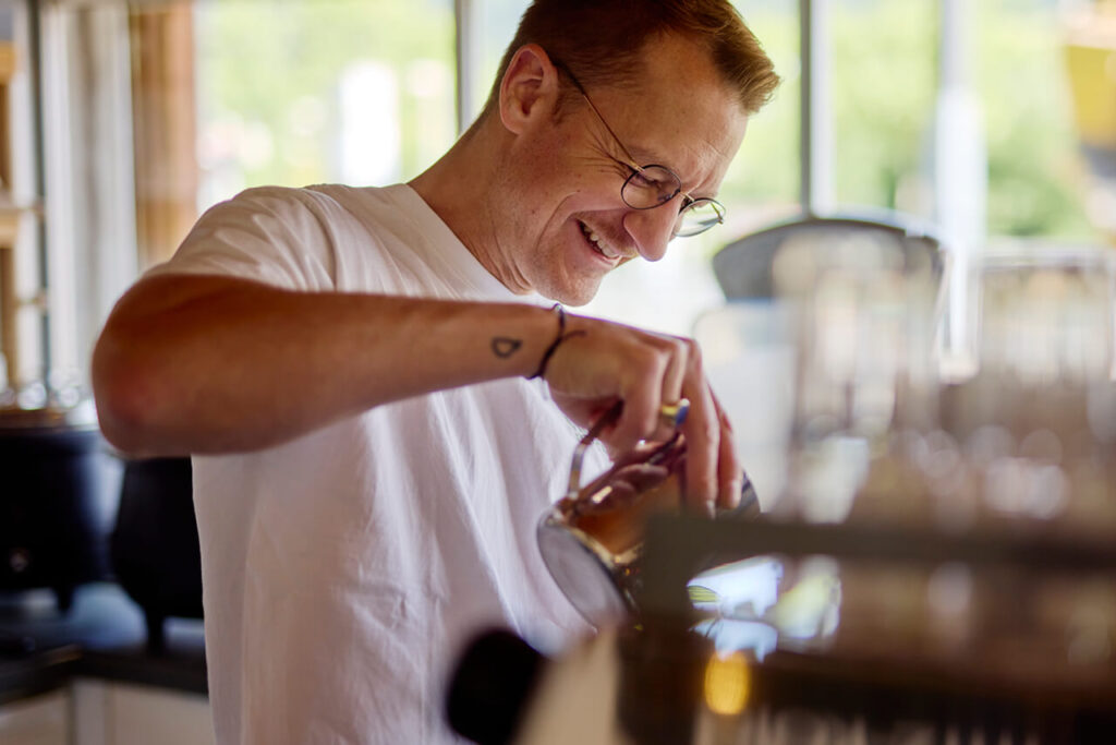 David Kienzler, Inhaber des Biosk Freiburg, bereitet mit einem Lächeln frischen Cappuccino zu.