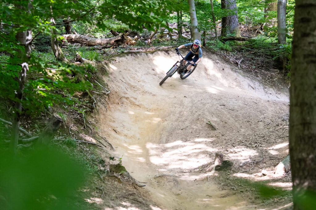 Lena Kehry fährt auf dem Mountainbike eine steile Kurve im Wald bei Freiburg – Teil des Trailnetzwerks vom Verein MTB Freiburg e. V.