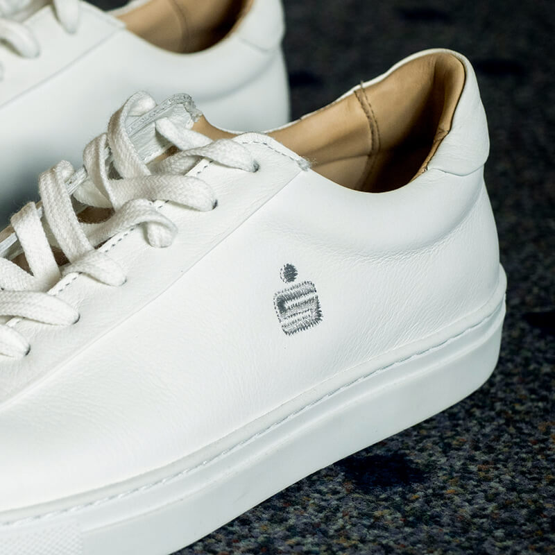 Weiße Sneaker mit gesticktem Sparkassenlogo auf dem seitlichen Schaft.