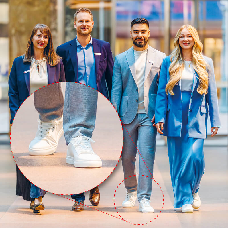 Vier Sparkassenmitarbeitende gehen nebeneinander in stilvoller Businesskleidung. Der Fokus liegt auf den weißen Sneakern, die im Bild vergrößert hervorgehoben sind.
