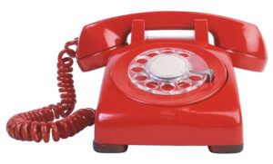 Rotes Wählscheibentelefon mit Hörer und Spiralkabel, frontal auf weißem Hintergrund fotografiert.