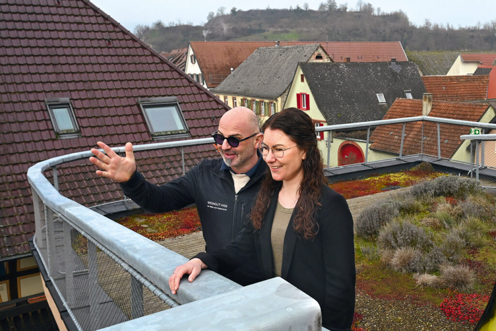 Winzer Andreas Hiss und Sparkassenberaterin Lenja Kraft stehen auf der Dachterrasse des Weinhauses Hiss in Eichstetten mit Blick über den Ort.