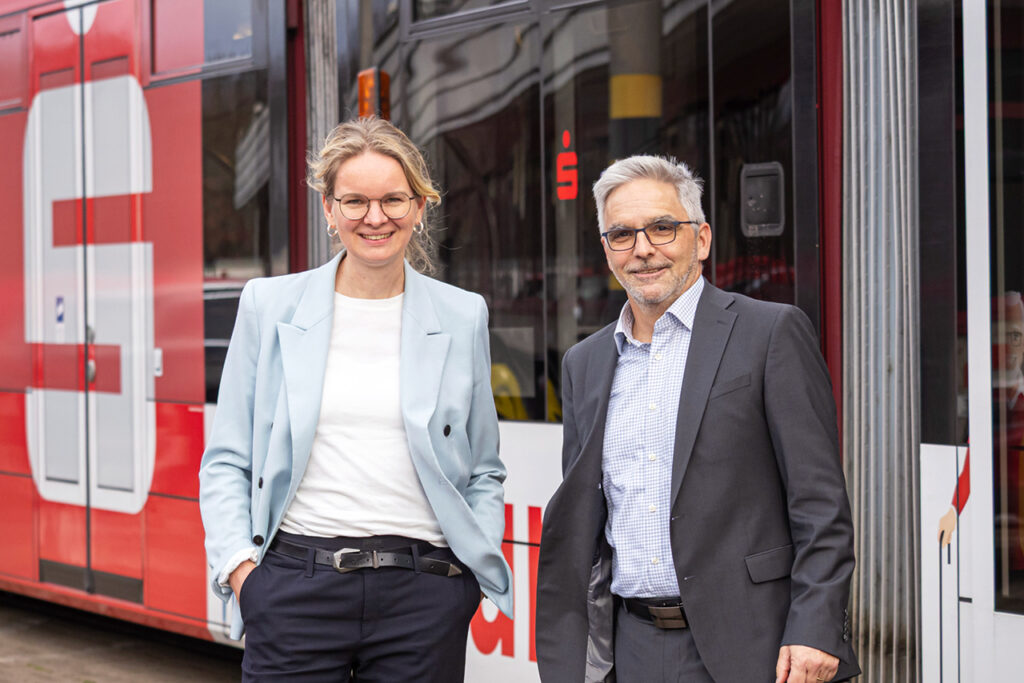 Mareike Rehl und Uwe Schlupf stehen vor einer Straßenbahn mit Sparkassen Gestaltung.