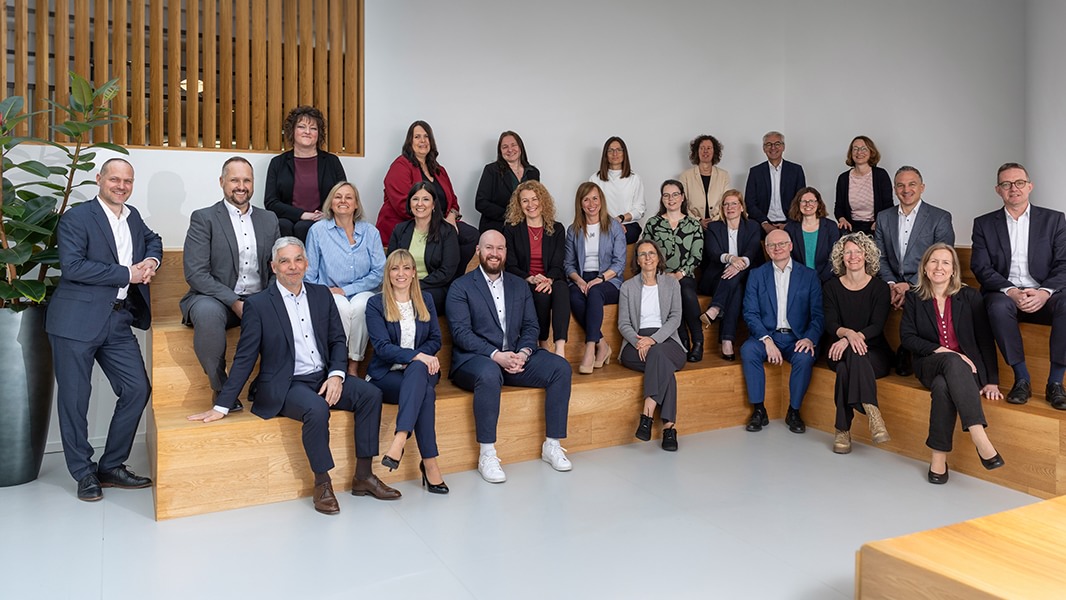 Teamfoto auf einer Holztreppe in einem modernen Innenraum