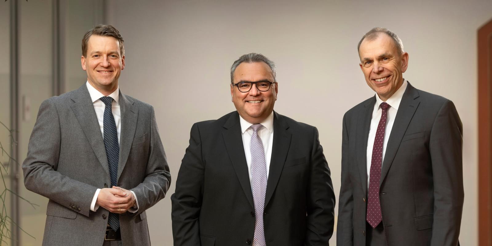 Die drei Vorstandsmitglieder der Sparkasse Freiburg-Nördlicher Breisgau, Philipp Plath, Daniel Zeiler und Bernd Rigl, in einem Innenraum.
