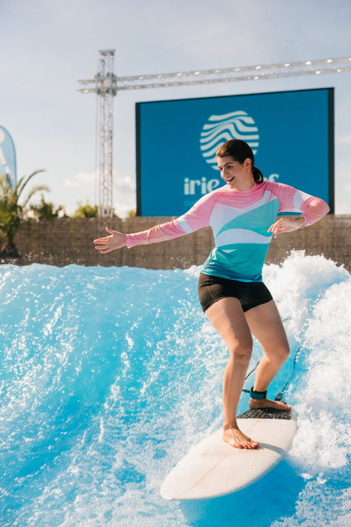Frau reitet Welle in Surfbekleidung auf Surfbrett